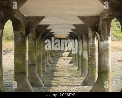 Stone columns under an old bridge during daylight Stock Photo