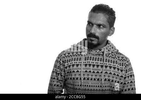 Portrait of young handsome bearded Indian man wearing hoodie Stock Photo