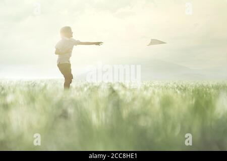 young boy makes his paper airplane fly in a meadow Stock Photo