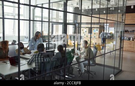 Business meeting. Group of happy smiling multiracial business people discussing project, working together while sitting in a conference room in the Stock Photo