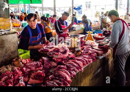 Tachileik, Myanmar - February 8, 2019: Male merchants in their stand selling meat in the wet market in Myanmar. The men are offering red meat. Stock Photo