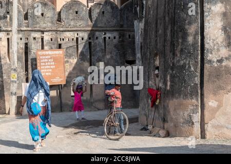 Orchha, Madhya Pradesh, India - March 2019: A young Indian boy standing with his bicycle and talking to an elderly hermit outside the ancient walls of Stock Photo