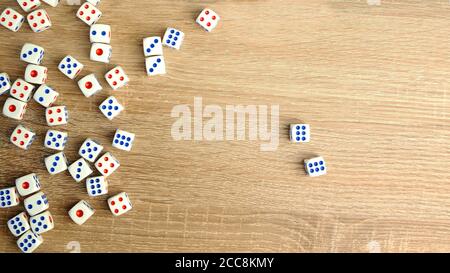 Many white dice with red and blue dots on wooden table. Casino gambling concept. Close-up. Indoors. Stock Photo