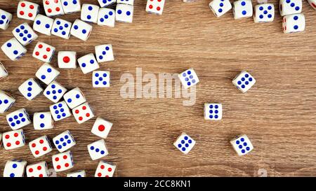 Many white dice with red and blue dots on wooden table. Casino gambling concept. Close-up. Indoors. Stock Photo