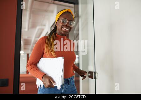 Portrait of African young businesswoman smiling at camera while going into the office at meeting Stock Photo