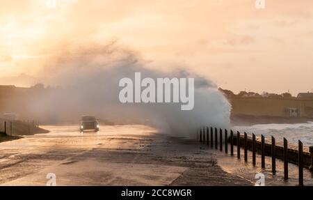 Garrettstown, Cork, Ireland. 20th August, 2020. A car slowly makes its way on the coast road as waves crash over the sea wall in the aftermath of Storm Ellen in Garrettstown, Co. Cork, Ireland.- Credit; David Creedon / Alamy Live News Stock Photo