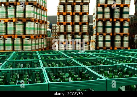 Germany Brewery. Box with bottles of beer at first plan and pallets of beer kegs in stock outdoor brewery on background. Stock Photo