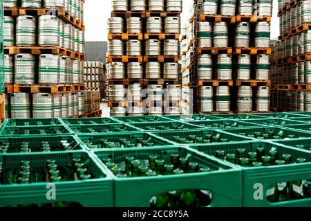 Germany Brewery. Box with bottles of beer at first plan and pallets of beer kegs in stock outdoor brewery on background. Stock Photo