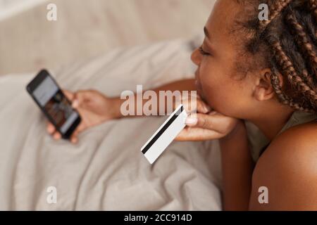 Close-up of woman paying with her credit card on the phone while lying in her bed Stock Photo
