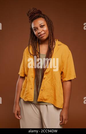 Portrait of fashion African woman with stylish hairstyle smiling at camera against the brown background Stock Photo