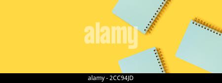 Banner with mint spiral notebooks on a yellow background. Cute school supplies. Stock Photo