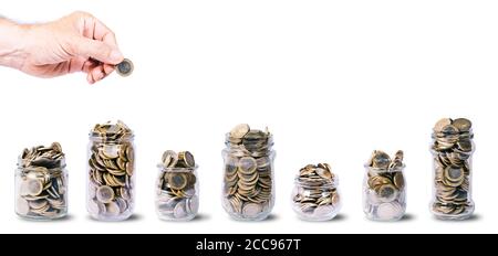 Male hand with a euro coin on different types of glass jars, filled with euro coins. On white background with copy space Stock Photo