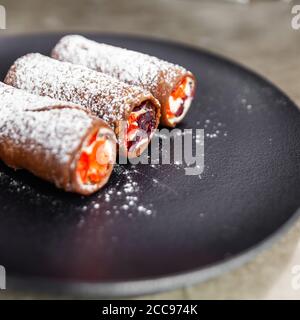 Traditional italian dessert cannoli on black plate. Stock Photo