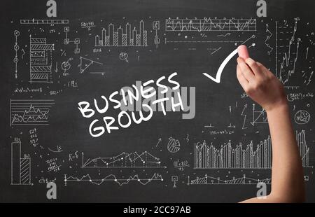 Hand drawing BUSINESS GROWTH inscription with white chalk on blackboard, new business concept Stock Photo