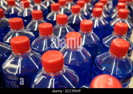 Dark blue fluid in the plastic bottles with red caps. Stock Photo
