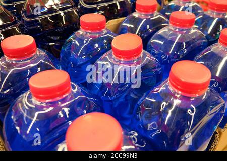 Dark blue fluid in the plastic bottles with red caps. Stock Photo