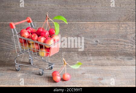 Shopping concept. Shopping cart with red apples on wooden background with copy space Stock Photo