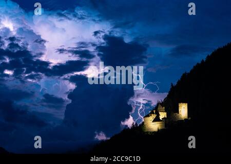 Lightning bolt strikes down from a stormcloud, close to a castle in the mountains Stock Photo