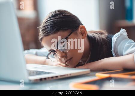 Surprised brunette girl in eyeglasses napping at the laptop Stock Photo
