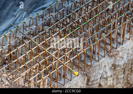 Industrial rebars used for reinforcement during piling construction process. Rusty steel metal threaded rods on concrete in building site. Overhead Stock Photo