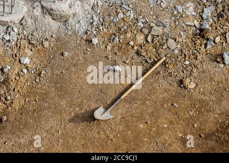 Spade shovel with long handle, tool used for digging, lying on soil ground with rubble rocks and copy space. Concept building site, construction Stock Photo