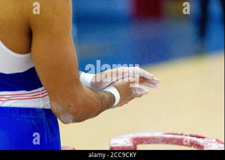 Gymnast of the French national team using chalk to dry his hands during a Men's Artistic Gymnastics event