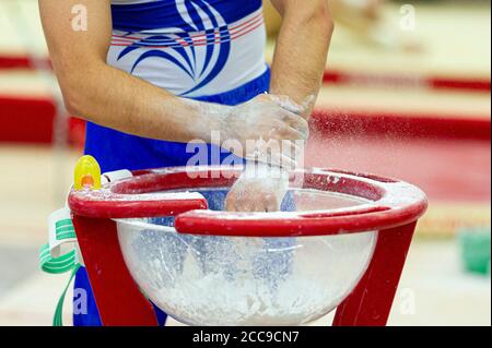 Gymnast of the French national team using chalk to dry his hands during a Men's Artistic Gymnastics event