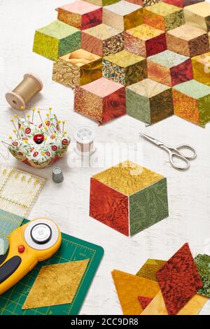 Fragment of tumbling blocks quilt, accessories for quilting on a white surface Stock Photo