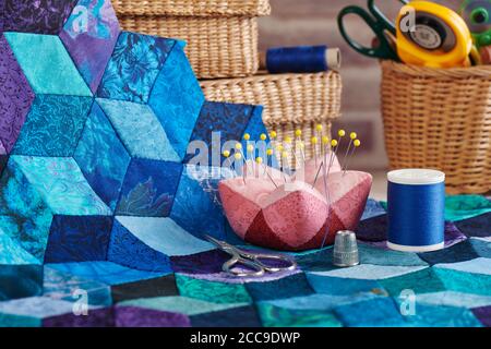 Accessories for sewing, fragment of tumbling blocks quilt and baskets with tools for sewing and quilting on a brick wall background Stock Photo