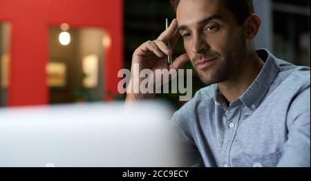 Focused young businessman working on a laptop at his desk Stock Photo