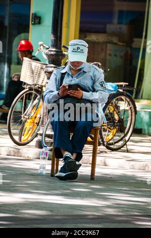 A parking assistant using her mobile phone near the entrance to Fuxing Park off Nanchang Lu in Shanghai. Stock Photo