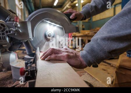 Carpenter cutting flaxboard using sliding compound mitre saw Stock Photo