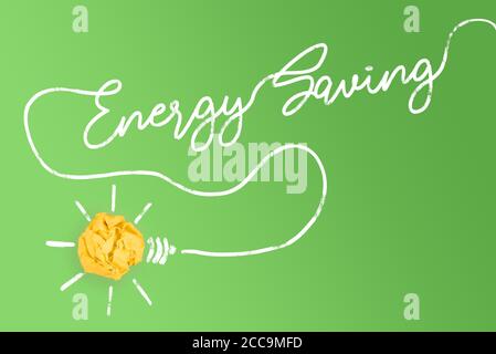 yellow paper ball light bulb with cable forming text ENERGY SAVING, sustainability concept Stock Photo