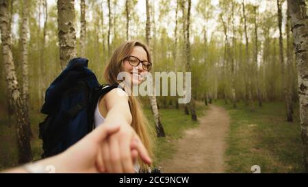 Hiker woman holding man's hand and leading him in forest. Couple in love. Point of view shot. High quality photo Stock Photo