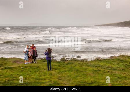 Garrettstown, Cork, Ireland. 20th August, 2020. French visitor Axeller Josselin takes a picture for the Madigan family from Kilkenny with a backdrop of the Wild Atlantic Way in the aftermath of Storm Ellen at Garrettstown, Co. Cork, Ireland. - Credit; David Creedon / Alamy Live News
