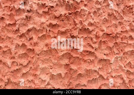 The surface of the cement wall makes it rough. It is an unusual texture with a reddish pink color. Stock Photo