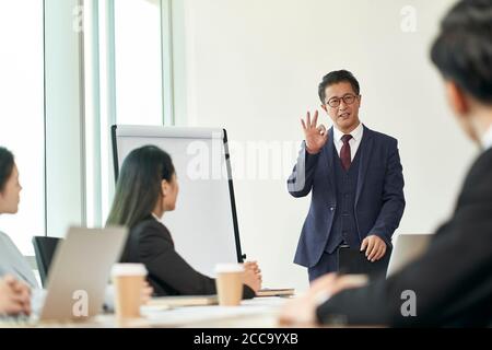 asian corporate executive delivering a speech during team meeting in office Stock Photo