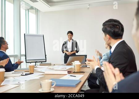 young asian junior executive applauded by colleagues and coworkers after speech Stock Photo