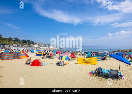 The crowded beach and seafront in high season at Lyme Regis, a popular seaside holiday resort on the Jurassic Coast in Dorset, south-west England Stock Photo