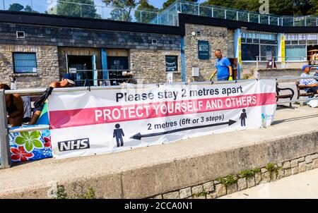 Banner on the beach promenade: Please stay 2 metres apart. Lyme Regis, a popular seaside holiday resort on the Jurassic Coast in Dorset, SW England Stock Photo