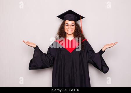 Young woman wearing graduation uniform very happy and excited, winner expression celebrating victory screaming with smile and raised hands Stock Photo