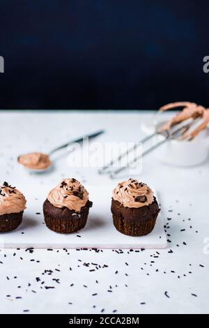 Tasty chocolate muffins with chocolate cream on top placed on the white background. Stock Photo