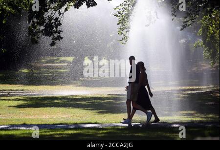 Berlin, Germany. 20th Aug, 2020. At temperatures around 30 degrees Celsius, people walk through the zoo, which is watered by a lawn sprinkler. Credit: Wolfgang Kumm/dpa/Alamy Live News Stock Photo