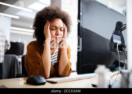 Overworked and frustrated young woman in front of computer in office Stock Photo