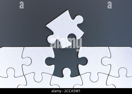 White jigsaw puzzle pieces on gray background Stock Photo
