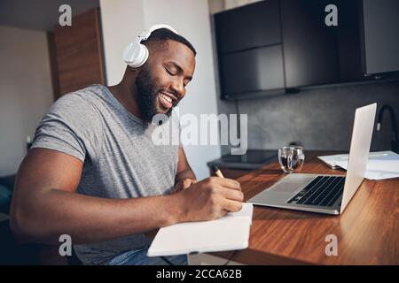 Cheerful bearded man making notes in notebook Stock Photo