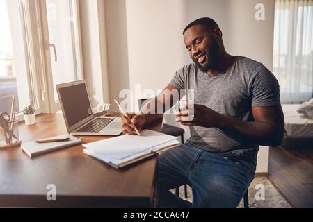 Positive delighted male person making notes during talk Stock Photo