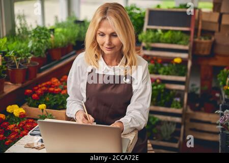 Concentrated blonde lady working in a floral shop Stock Photo