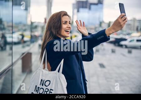 Young beautiful lady laughing and waving hand in camera Stock Photo