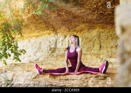 A young woman athlete performs leg stretching in the fresh air against the wall. The concept of a healthy lifestyle Stock Photo